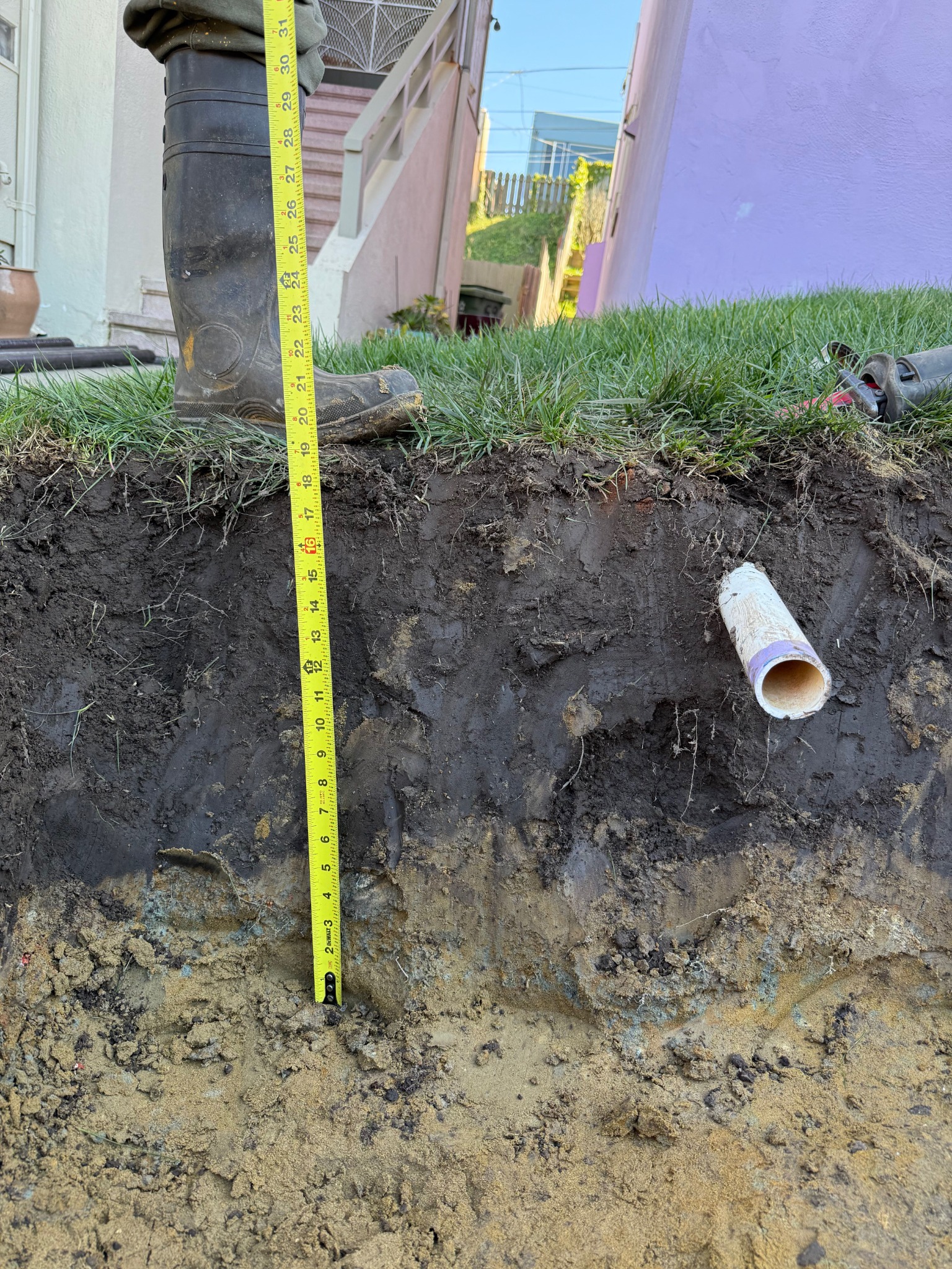 A Facilities Plumbing And Drain technician measures during a curb drain installation.