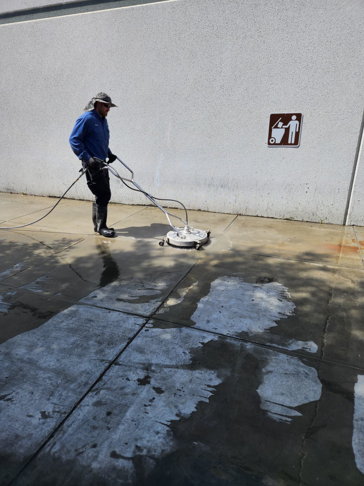 A Facilities Plumbing And Drain technician completing pressure washing.