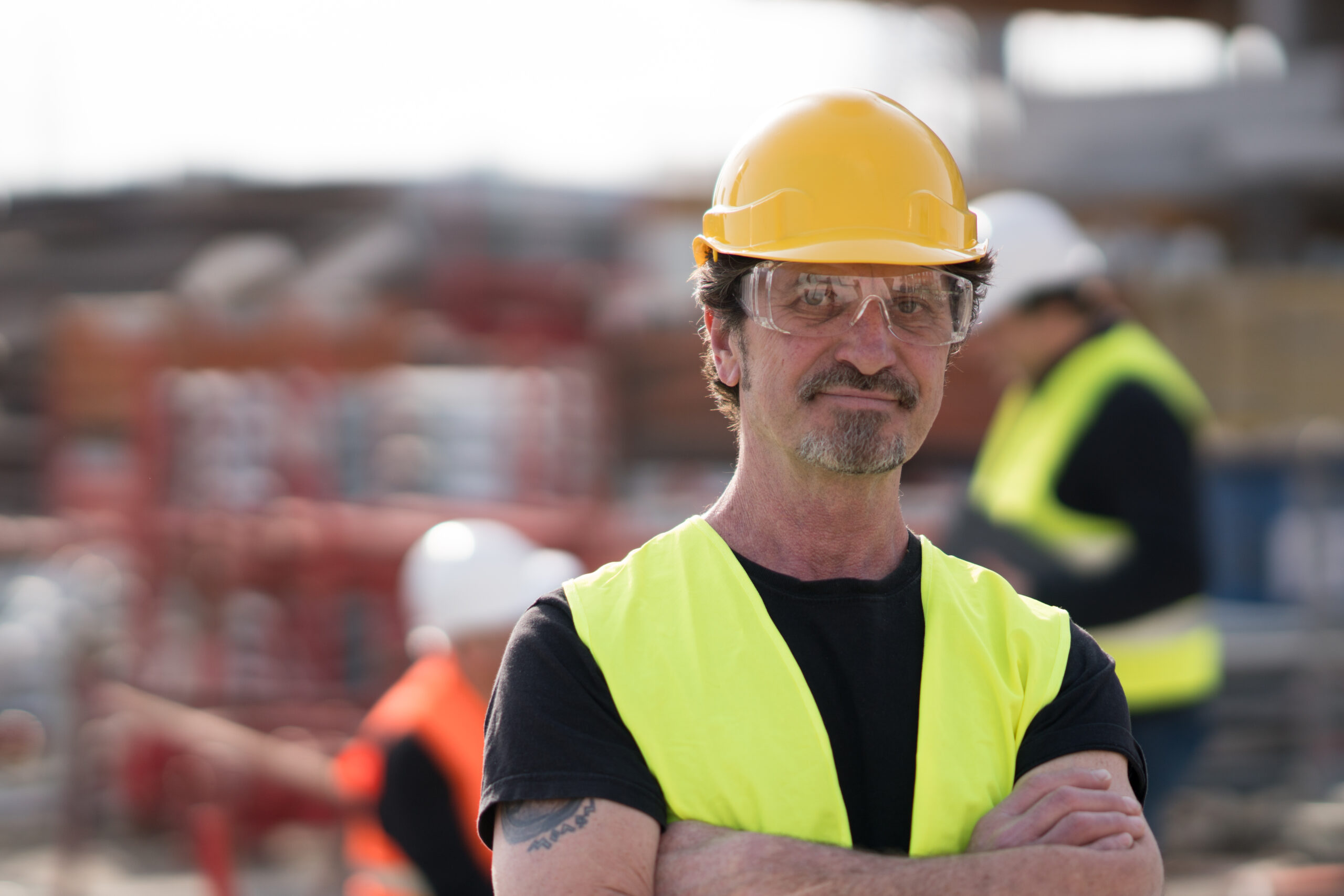 A plumber with a safety vest and hard hat smiling at a Berkeley, CA job site.