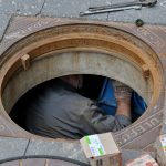 Pro plumber with Facilities Plumbing & Drain works inside commercial manhole in the Bay Area