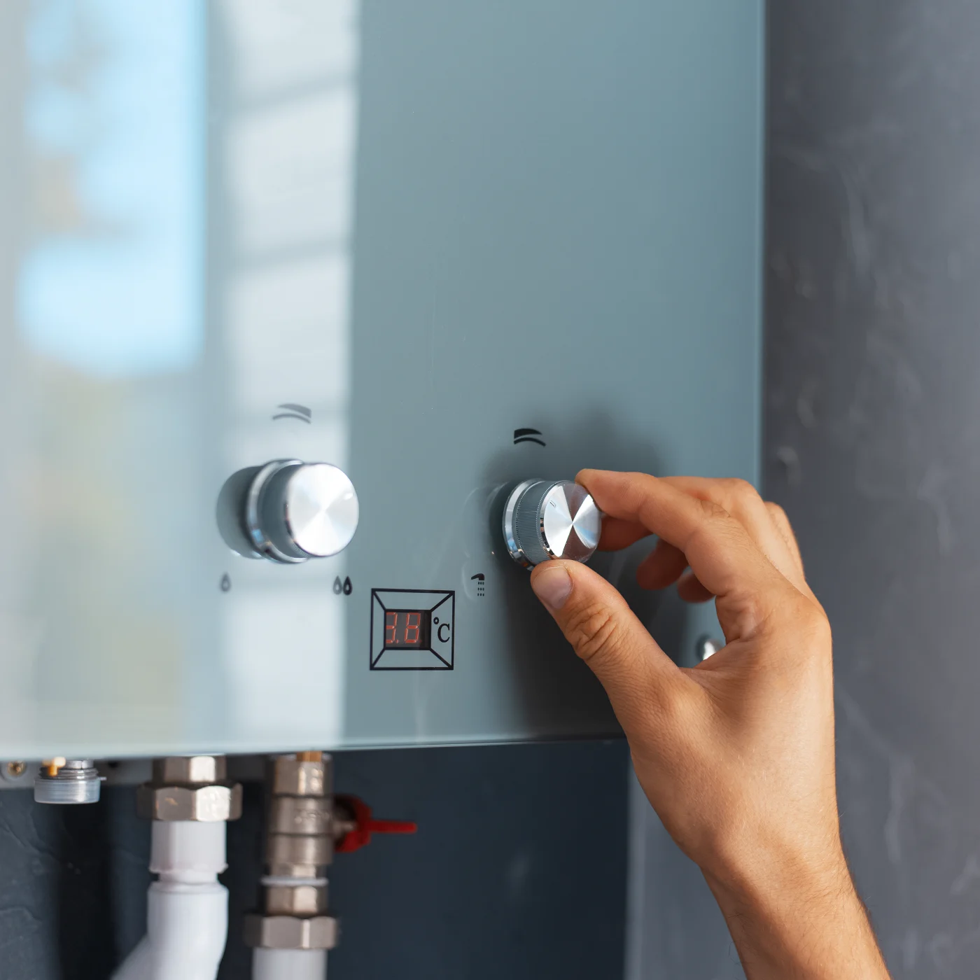 Someone adjusting the temperature on a modern water heater with dials.
