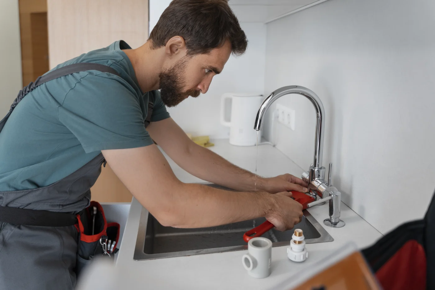 A plumber working on kitchen sink pipes in a Hayward, CA home.