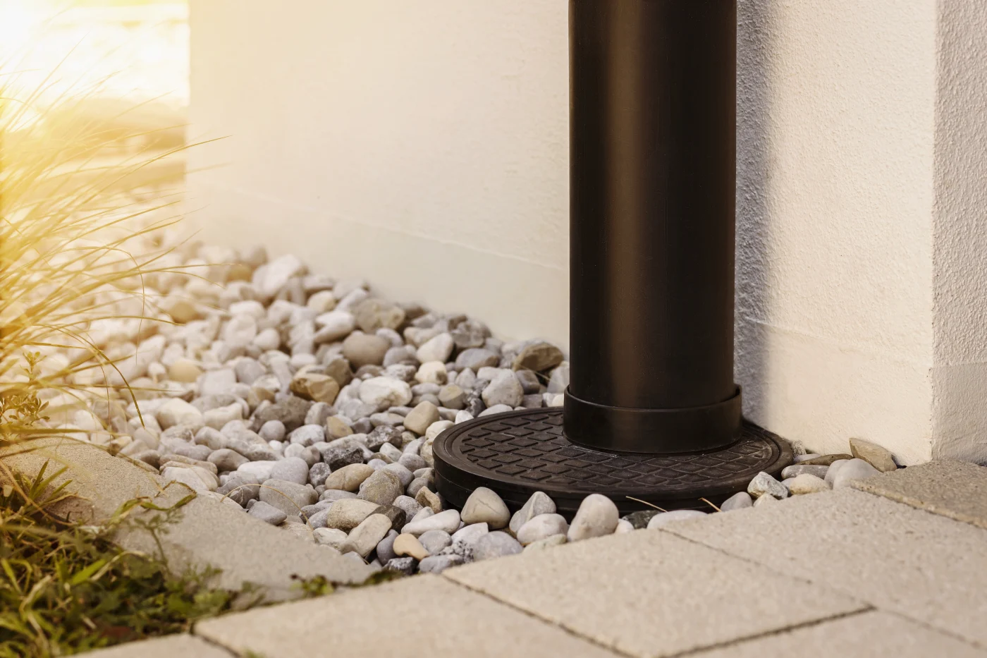 A drain pipe installed on the side of a home, leading down to the foundation.