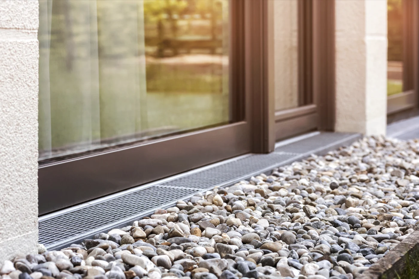 Great Foundation Drains in San Francisco, CA | Facilities Plumbing & Drain A foundation drain along sliding glass doors and river rock gravel in San Francisco, CA.