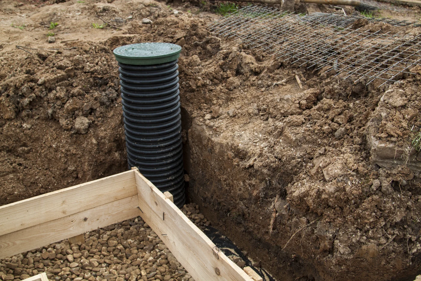 A pipe in the dirt next to a foundation in the process of being built.