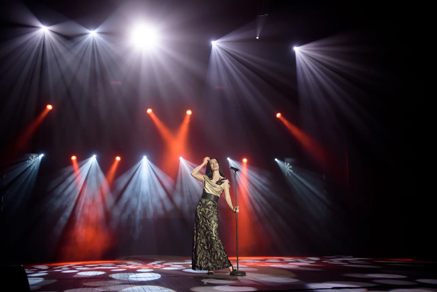 Cutting-Edge Commercial Plumbing Services | San Francisco Bay Area | Facilities Plumbing & Drain A female singer in an elegant dress at a microphone on stage, under multiple spotlights.